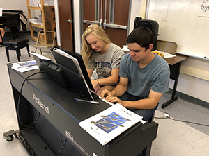 Two students playing the piano together in the music appreciation class